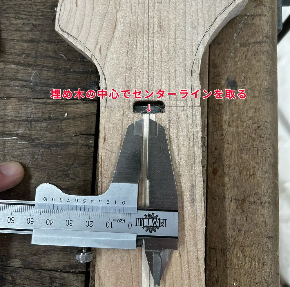 ベースギターのネックの埋め木の中心でセンターラインを測っているところ