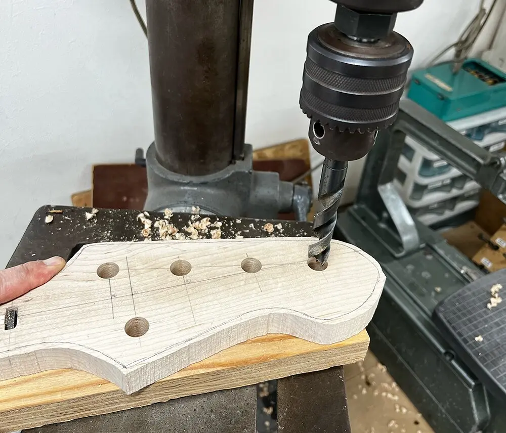 ベースギターのヘッドにペグ穴をボール盤で開けているところ