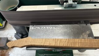 ギター用のローステッドフレイムメイプル材のグリップ面をベルトサンダーで平面出し