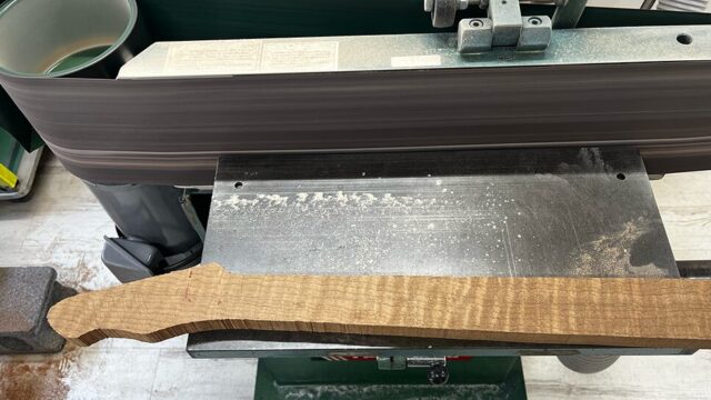ギター用のローステッドフレイムメイプル材のグリップ面をベルトサンダーで平面出し