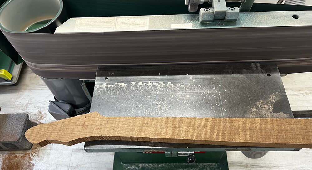 ギター用のローステッドフレイムメイプル材のグリップ面をベルトサンダーで平面出し