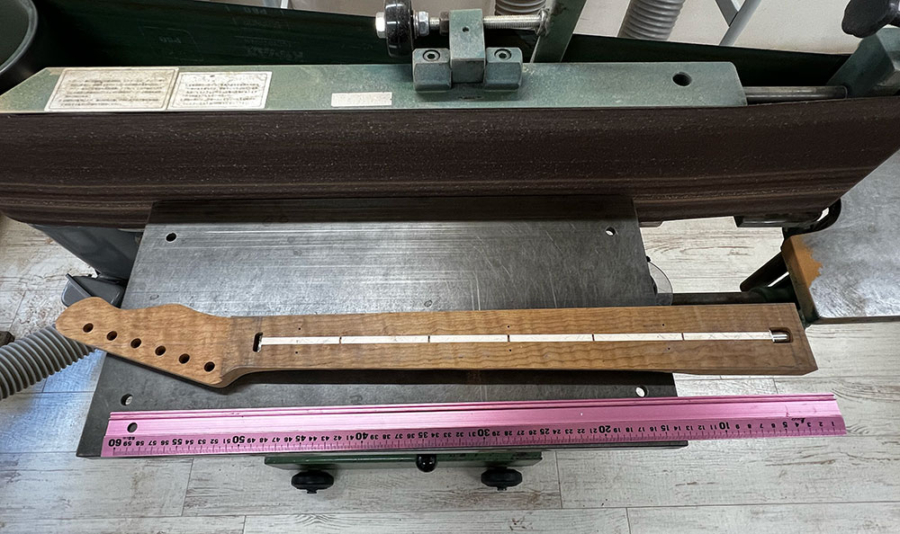 ギターのネックの指板接着面をエコノミーサンダーで削って平面にしているところ