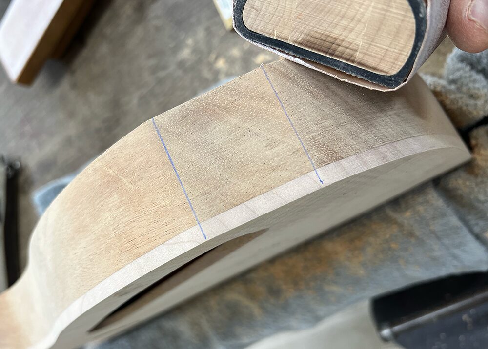 ギターボディ外周のジャック周りを#150のサンドペーパーで磨いているところ