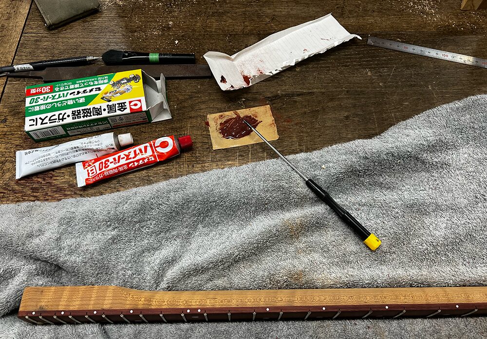 サティーネ指板のフレットサイドをエポキシで埋めているところ