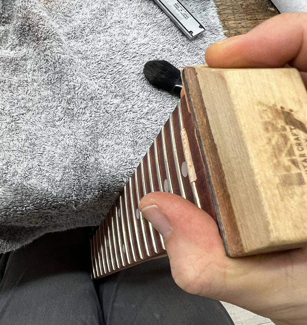 ギターネックのエンド部分を台形のパッドで磨いているところ