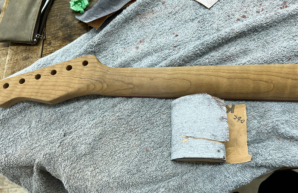 ギターのフレイムメイプルネックを#240のサンドペーパーで磨いているところ