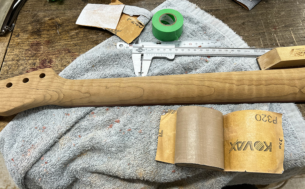 ギターのフレイムメイプルネックを#320のサンドペーパーで磨いているところ