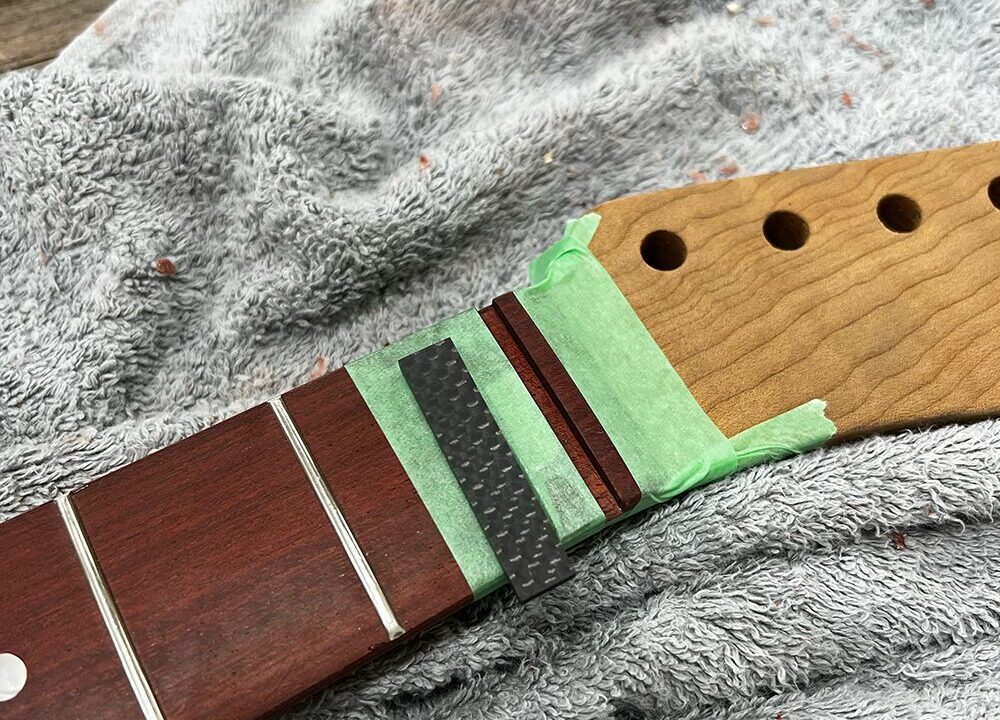 ギターのナット溝にカーボンナットをはめようとしているところ