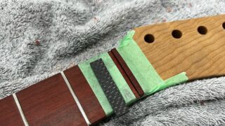 ギターのナット溝にカーボンナットをはめようとしているところ