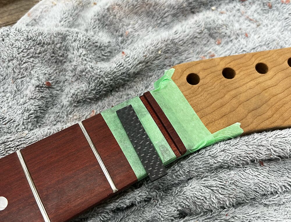 ギターのナット溝にカーボンナットをはめようとしているところ