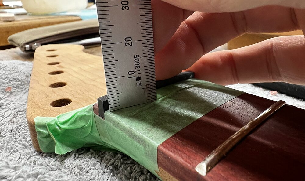 ギターのネックのナット溝にはめ込んだカーボンナットの6弦側の高さを150mmスケールで計測