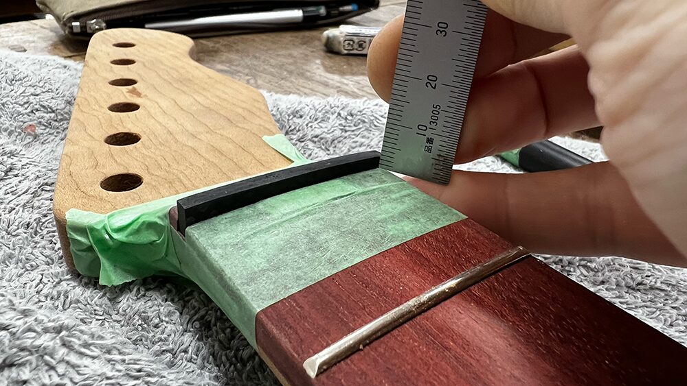 ギターのネックのナット溝にはめ込んだカーボンナットの1弦側の高さを150mmスケールで計測