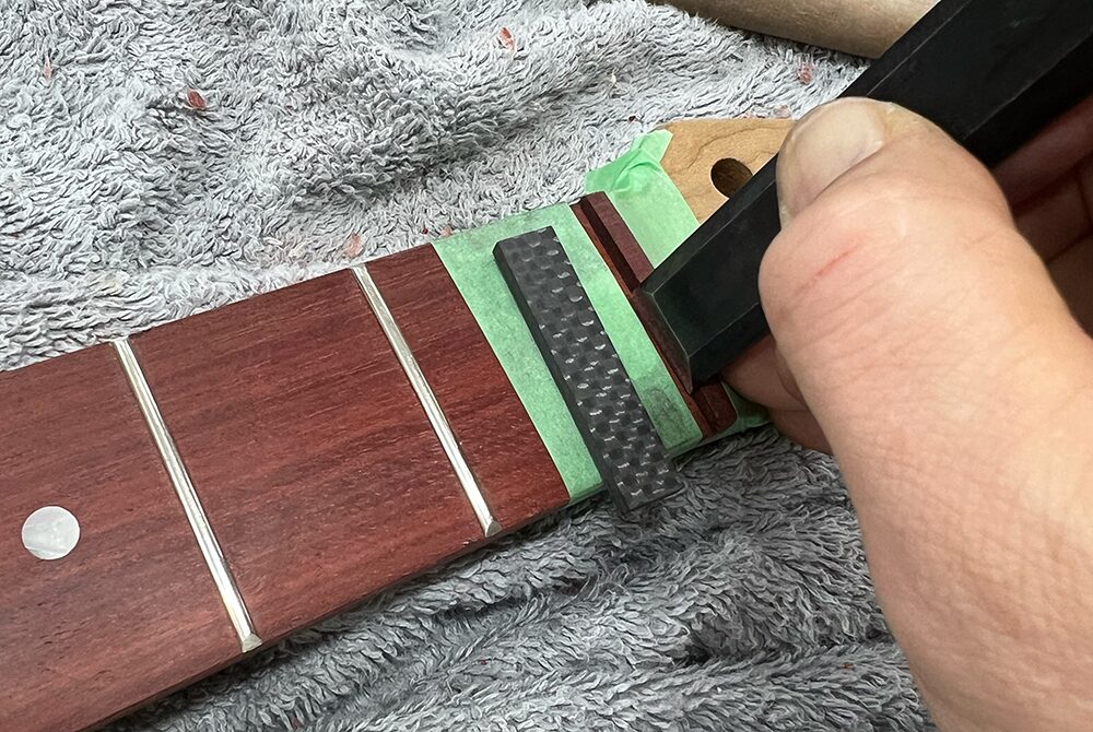 ギターのナット溝の段差を仕上げノミで削っているところ