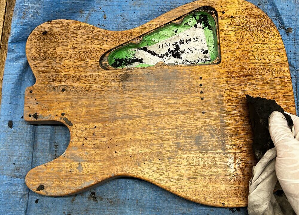 シンラインタイプのギターボディに塗ったウッドフィラーを拭いているところ