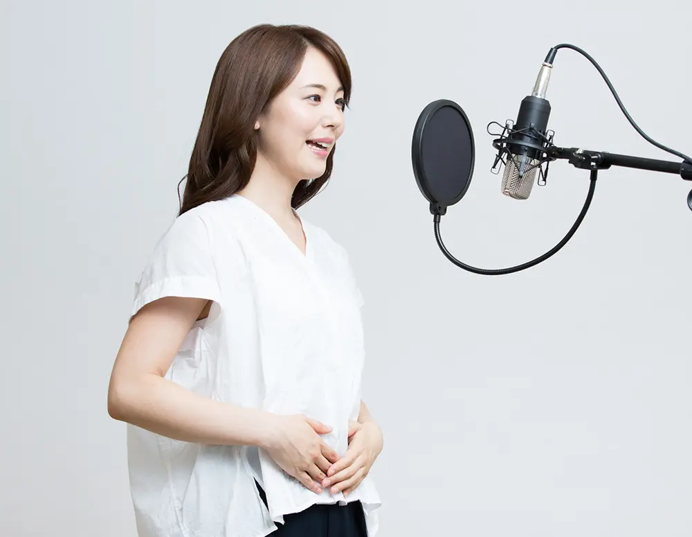 腹式呼吸のためにお腹に手をあてて発声練習している女性